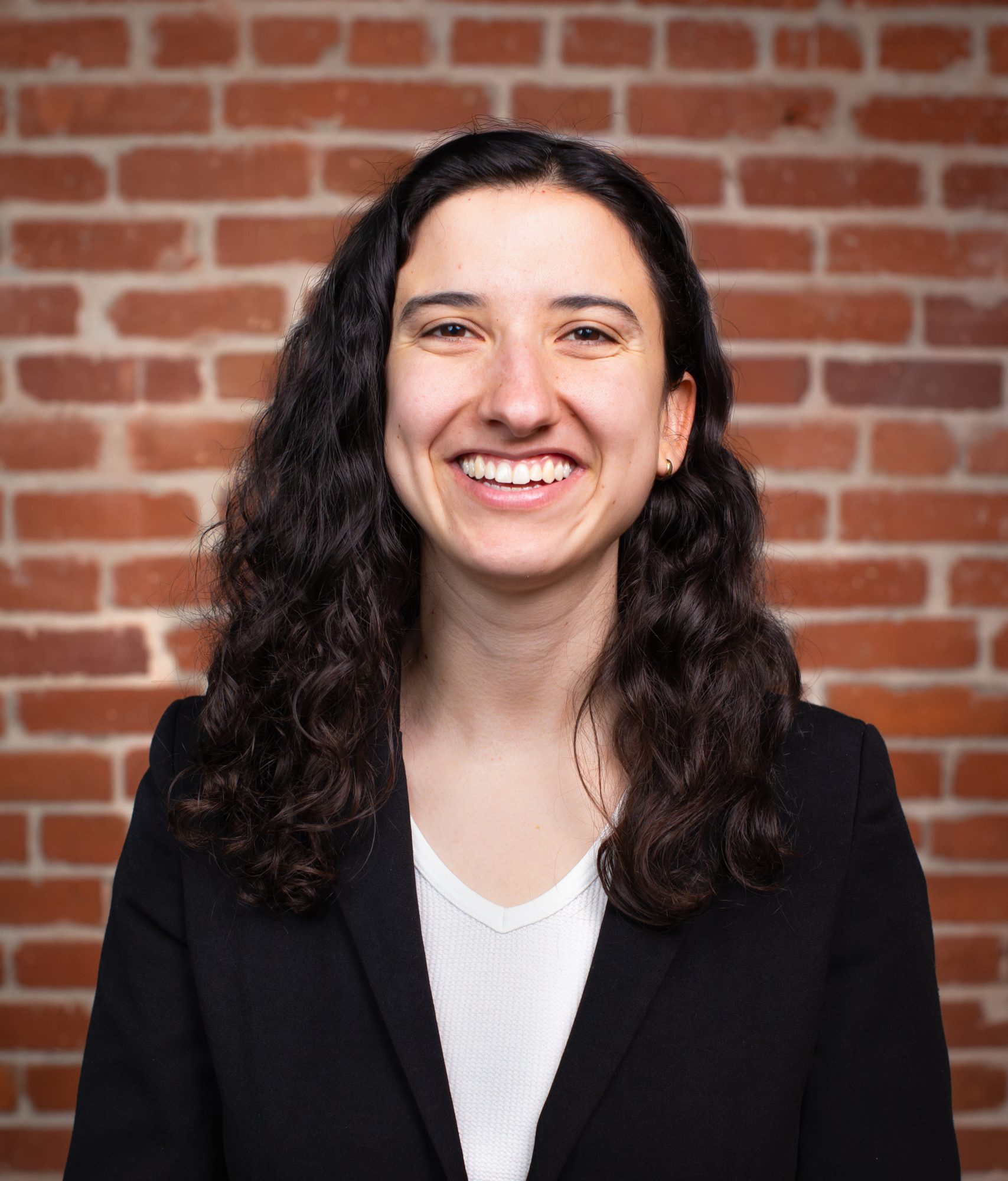 Portrait of Lia Cohen smiling in front of a brick wall, associated with Climate Resolve