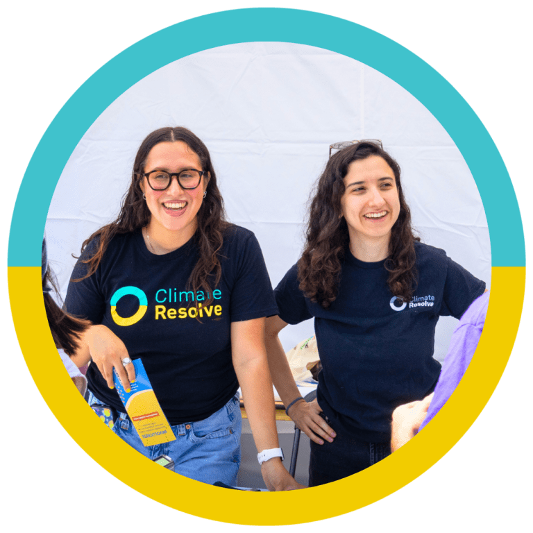 Two Climate Resolve team members smiling and engaging with attendees at an outreach table