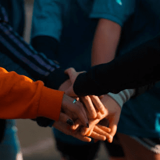 PACE graphic showing a close-up of several people placing their hands together in a stack, symbolizing teamwork and collaboration
