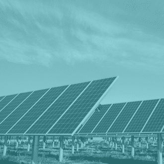 Rows of solar panels installed in an open landscape under a cloudy sky, shown with a teal color overlay