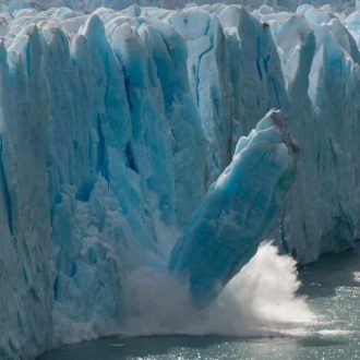 Large chunk of glacier ice breaking off and falling into the ocean, illustrating melting ice and climate change impacts