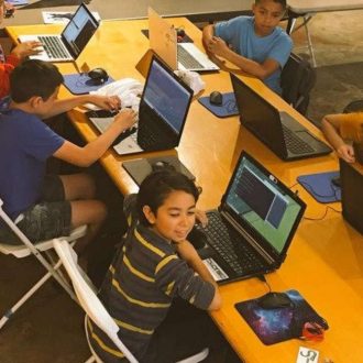 Group of students using laptops at a table, representing youth engagement, digital learning, and climate education programs